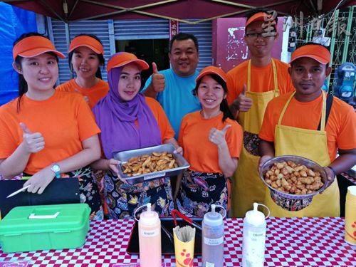 潘俊庆(后排中)和员工们以独家秘方调制的快餐获得顾客好评。(图：星洲日报)