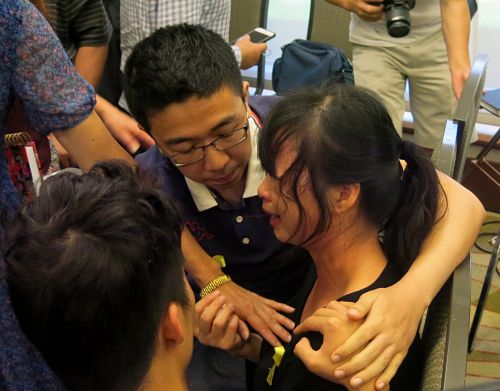 章莹颖(右)母亲痛哭，章莹颖弟弟(左)与男友(中)在旁安慰。(美国侨报网)