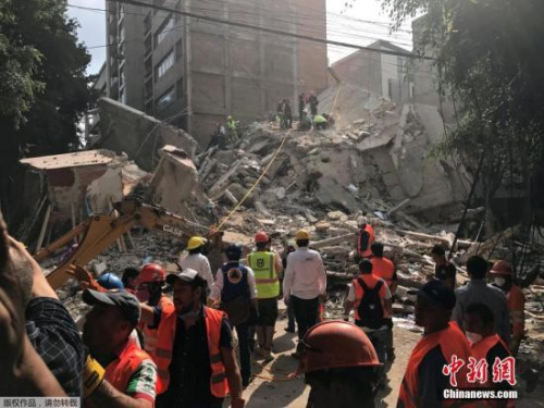 墨西哥城的一处楼房废墟上，救援人员正在进行清理搜救工作。