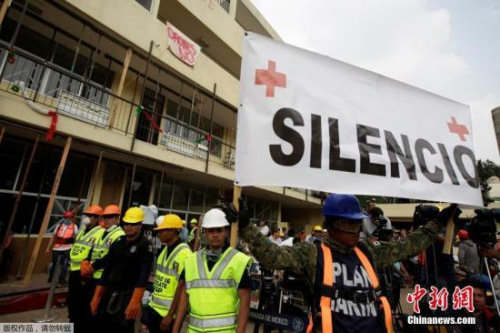 当地时间9月21日，墨西哥首都墨西哥城地震救援人员举起拳头示意保持安静，这样才能更好的听到废墟下的声音。