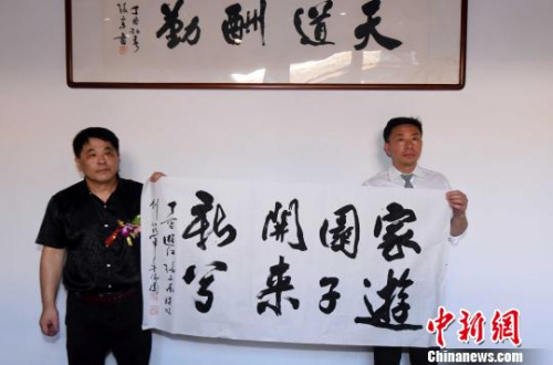参展书法家美国侨胞游江(右)、张文东(左)现场展示由他们联袂挥毫题写的书法作品。　记者刘可耕 摄