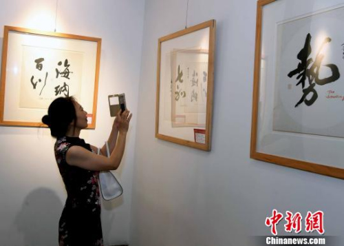 一名女性观众用手机拍摄参展书法作品。　记者刘可耕 摄