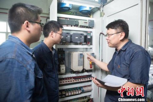 邓建军和同事们探讨设备情况。 江苏常州黑牡丹(集团)股份有限公司供图。 邓建军和同事们探讨设备情况。 江苏常州黑牡丹(集团)股份有限公司供图。