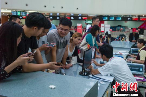 图为海口美兰国际机场航站楼内服务台聚集了前来改签问询的旅客。 骆云飞 摄 图为海口美兰国际机场航站楼内服务台聚集了前来改签问询的旅客。 骆云飞 摄
