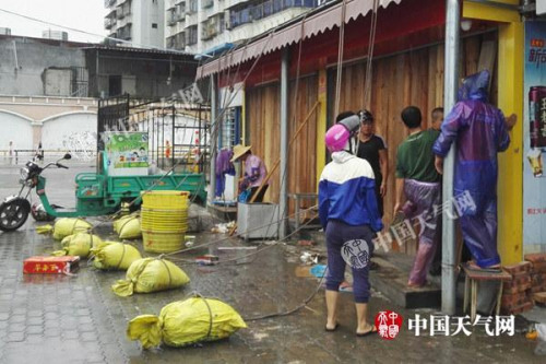 15日白天，广东湛江风雨逐渐明显，市民正在加固门窗。(图/殷美祥)