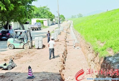 正在施工的北堤背水坡石护篱和排水道工程。　　本报记者 黄春生 摄 