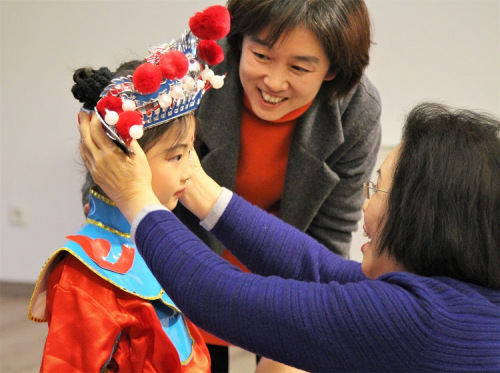 赵葆秀老师为即将表演的小朋友调整头饰。