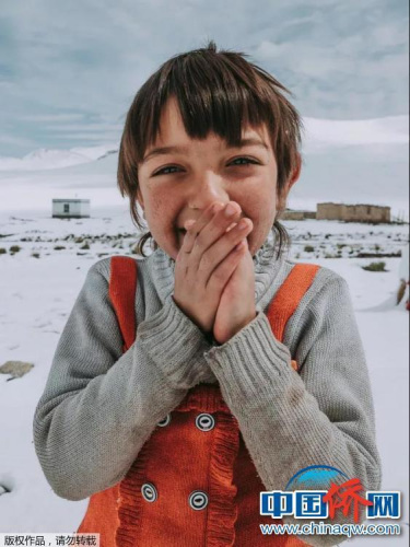 “相机摄”帕米亚高原，滚雪球的塔吉克族小女孩，正在给自己的小手哈气取暖。