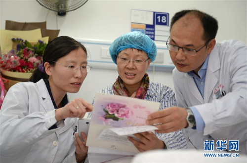郭璐萍(中)在观看即将援非的医疗队成员为她创作的诗歌和集体签名卡片。