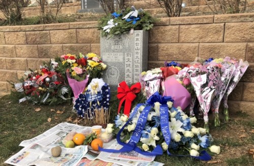 亲友们在刘文健墓碑前摆放着鲜花与他生前爱吃的糕点。(美国《世界日报》/黄伊奕 摄)