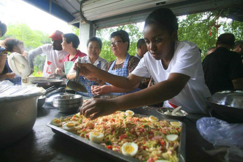 图2：2012年6月25日，温州医学院中外大学生暑期社会实践团学生来到红日亭帮厨，来自非洲的留学生们更为人们带来了异国风味的非洲美食。