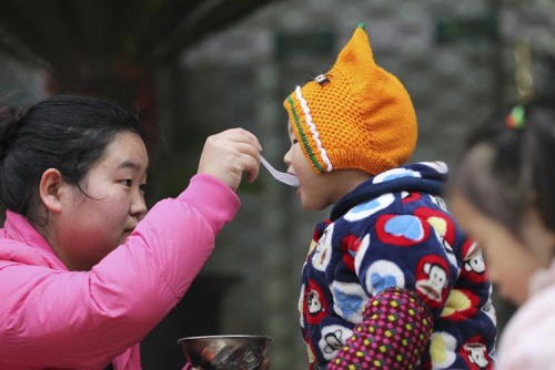 图3：2015年1月27日，腊八节，龙湾区永中街道永中东路一爱心施粥点，孩子们在津津有味品尝腊八粥。