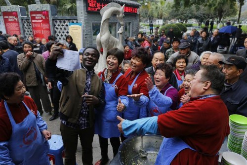 图7：2015年农历二月初二，当日来红日亭吃芥菜饭的路人很多，温州医学院留学生艾鹏达闻讯后来红日亭当义工。在场的红日亭老人们纷纷与艾鹏达开心留影。