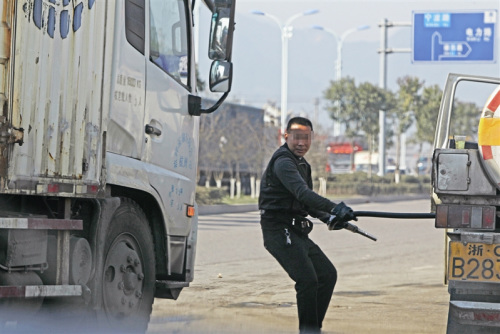 拔枪加油一名男子从油罐车上拔出加油枪，准备给货车加油