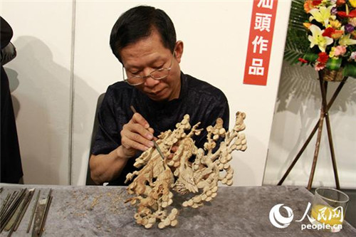 潮州木雕传承人何汉林正在雕刻花纹。(摄影：吴玉洁)
