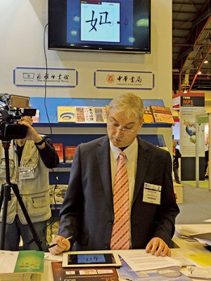 英国精制绘图公司总裁罗宾・伍兹在发布会现场演示汉语学习App的书写学习功能。(图：欧洲时报 侯清源摄)