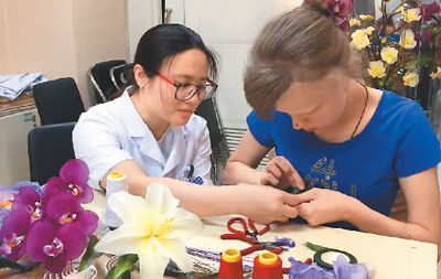 医护人员教俄罗斯患者玛莎制作手工丝网花。 　　中国康复研究中心博爱医院供图