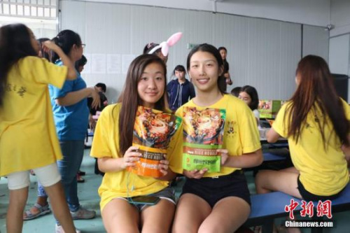 6月27日，2017年海外华裔青少年“中国寻根之旅”夏令营——民族风情城职营走进广西柳州市一家螺蛳粉生产企业。图为两名美国华裔青少年手捧袋装螺蛳粉合影。 林馨 摄