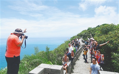 游客在文昌铜鼓岭景区一睹月亮湾美景和龙楼航天发射场风采。 本报记者 张茂 实习生 吴英艳 摄