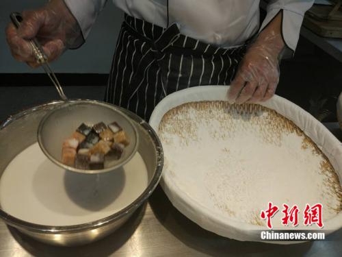 于伯军将馅料沾上水,准备投进盛满糯米粉的笸箩内摇。<a target='_blank' href='http://www.chinanews.com/' >中新网</a> 李金磊 摄 于伯军将馅料沾上水,准备投进盛满糯米粉的笸箩内摇。<a target='_blank' href='http://www.chinanews.com/' >中新网</a> 李金磊 摄