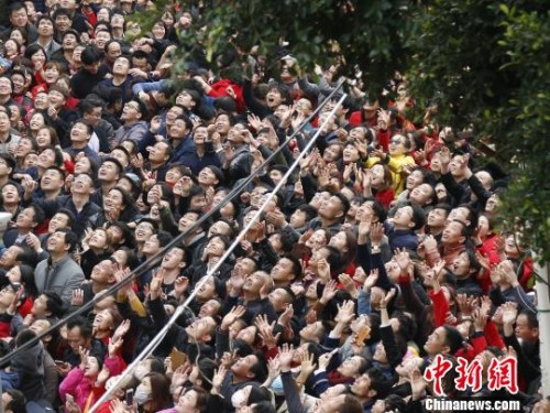 现场人群高举双手,大声呼喊,奋力接住“僮身”抛来的铜钱,以求平安、发财、好运。 林胜奕 摄 现场人群高举双手,大声呼喊,奋力接住“僮身”抛来的铜钱,以求平安、发财、好运。 林胜奕 摄