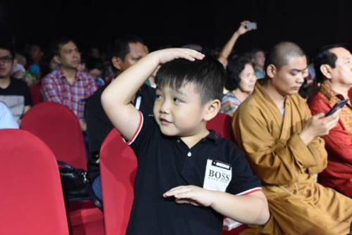 一位华裔小朋友在台下模仿武僧运气。