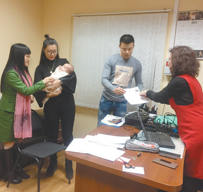 　　在伏尔加格勒，领事部工作人员于正荣(左一)和热娜(右一)，正在为刚出生的小宝宝办理相关证件。 本报记者 吴 焰摄