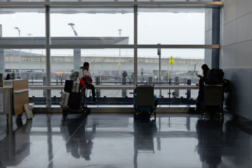 几名华人旅客21日在机场等待深夜红眼班机。(美国《世界日报》/朱泽人 摄)