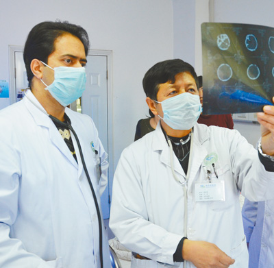 　2018年3月，比拉尔·海帝(左)与同事探讨病人病情。 　　神木市医院供图