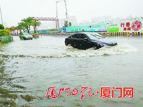 昨日中午，湖滨北路育秀路口积水，小车涉水前行。(本报记者黄少毅 摄)