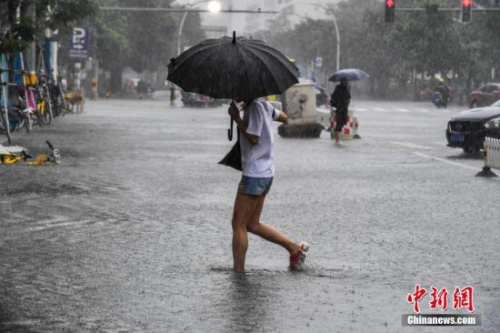 资料图：海口民众冒雨涉水出行。骆云飞 摄