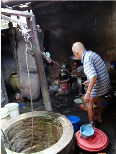 82岁的曾庆炮吃力的从井里打水供日常洗刷用途。（马来西亚《星洲日报》）