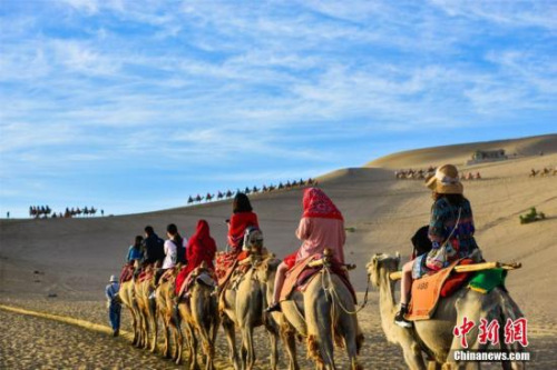 资料图：丝绸之路国际旅游名城甘肃敦煌，鸣沙山月牙泉人流如织、驼队如龙。王斌银 摄