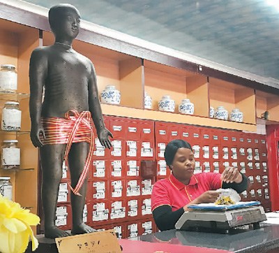 比勒陀利亚的一家同仁堂药店内，一名非裔员工正在称草药。