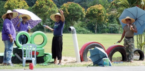 大家戴着草帽、撑着伞,在烈日下美化校园。(马来西亚《星洲日报》) 大家戴着草帽、撑着伞,在烈日下美化校园。(马来西亚《星洲日报》)