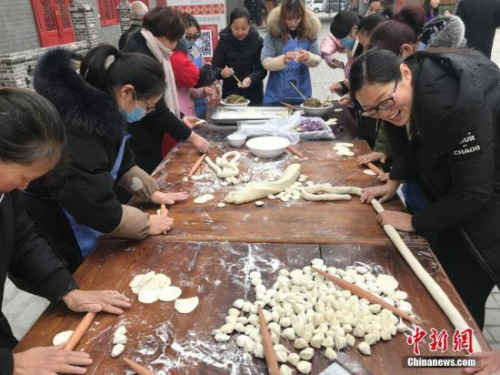 图为郑州村民、游客一起包饺子,其乐融融。 韩章云 摄 图为郑州村民、游客一起包饺子,其乐融融。 韩章云 摄