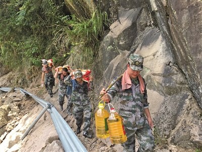 输送物资的小分队行走在塌方公路旁的陡峭山边。云岭乡供图