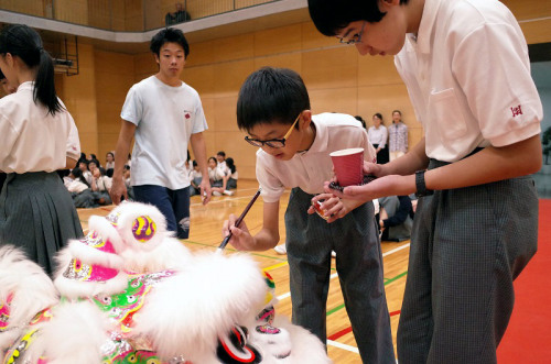 侨校学生为醒狮点睛。(日本《中文导报》)