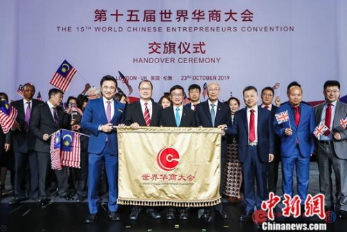 以“世界新格局，华商新机遇”为主题的第十五届世界华商大会当地时间10月22日至23日在伦敦举行。这是世界华商大会首次走进欧洲，在英国举行。在10月23日的闭幕式上，大会宣布2021年第16届世界华商大会将由马来西亚中华总商会主办。图为10月23日，英国中华总商会和马来西亚中华总商会举行交旗仪式。<a target='_blank' href='http://www.chinanews.com/'>中新社</a>发 王渊欣 摄 