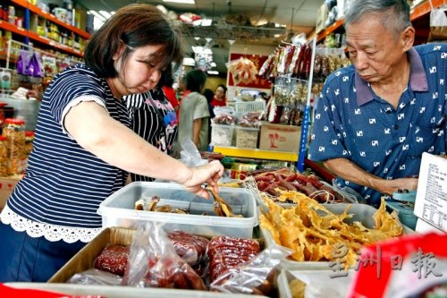 在店员的帮助下，民众仔细挑选腊鸭腿。(《星洲日报》/蔡伟传 摄)