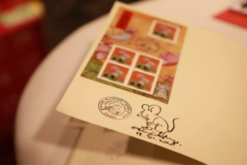 陈江洪在集邮爱好者的邮折上签名并画上一只小老鼠留念。(图片来源：欧洲时报记者欧文 摄)