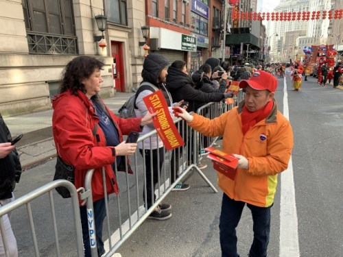 游行工作人员给民众发放写有"武汉加油"的手幅。(美国《世界日报》/和钊宇 摄)