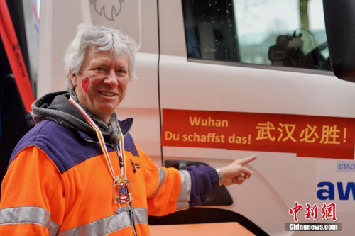 图为明斯特循环经济局（AWM）局长帕特里克·哈森坎普（Patrick Hasenkamp）给该局名下的一号花车两侧贴上“武汉必胜”的中德文标语。