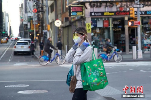 资料图：当地时间3月21日，美国纽约时代广场一位行人防护严密。 图片来源：中国新闻网