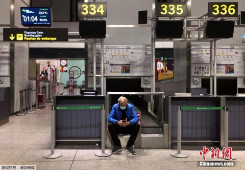 在西班牙马拉加的机场，一名男子戴着口罩等待他的航班起飞。