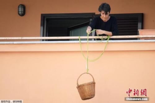 资料图：新冠肺炎疫情期间，意大利米兰，一名女士从阳台放下篮子，人们可以捐赠食物或免费享用篮子里的食物。