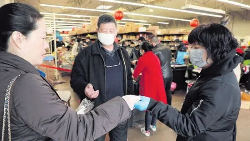 巴黎华助中心主任董晓燕(左)在欧拜赫维利耶一间华人超市发放口罩。(欧洲时报)