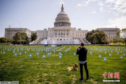 当地时间4月17日，新冠肺炎疫情期间，美国国会大厦西草坪上竖立起众多医疗工作者肖像照片，呼吁为医护提供个人防护设备。图为市民在照片上拍照。