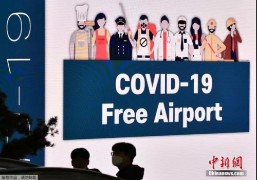 位于韩国首尔的仁川国际机场，戴着口罩的人们走过大屏幕。(中新网)