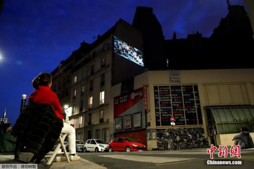 法国市民坐在路边欣赏露天电影。